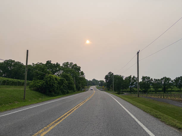 rodovia rural - dirigindo através de uma rodovia de pista simples com uma próxima ponte e um pôr do sol trote - single lane road road sunset rural scene - fotografias e filmes do acervo