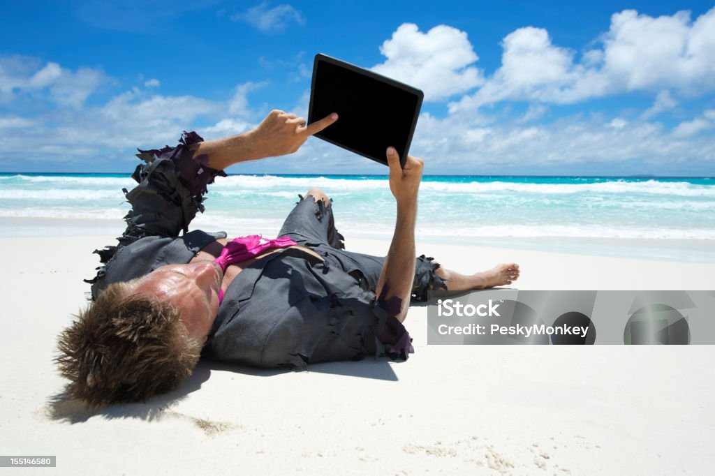 Náufrago empresario con tableta en la playa - Foto de stock de Actividades recreativas libre de derechos