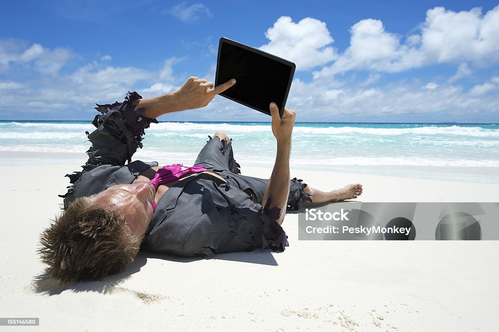 Rozbitek Biznesmen przy użyciu komputera typu Tablet na plaży - Zbiór zdjęć royalty-free (Białe kołnierzyki)