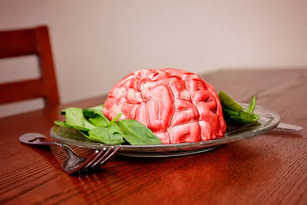 A brain sits on a plate of leafy salad.