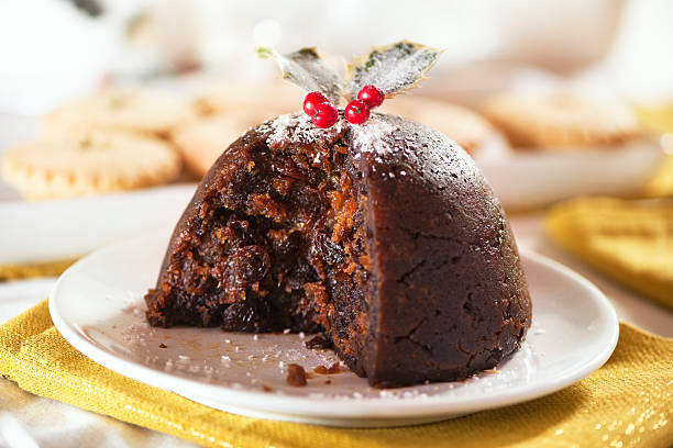Christmas pudding Christmas pudding with holly and mince pies in background and white and gold table colours. See also: christmas pudding stock pictures, royalty-free photos & images