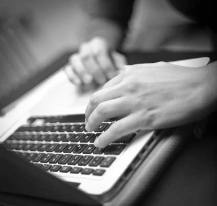 Close up of hands typing on laptop keyboard. Very shallow depth of field. Focus on one hand only.