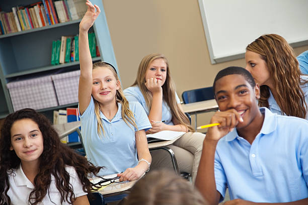 istock Pretty girl student raising her hand in class with students around her. 155147513