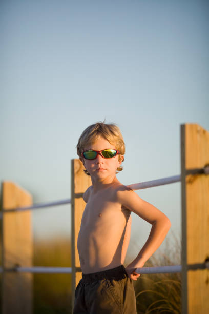 istock Blonde Boy Leaning Against Rope Fence at Sunset 155147545