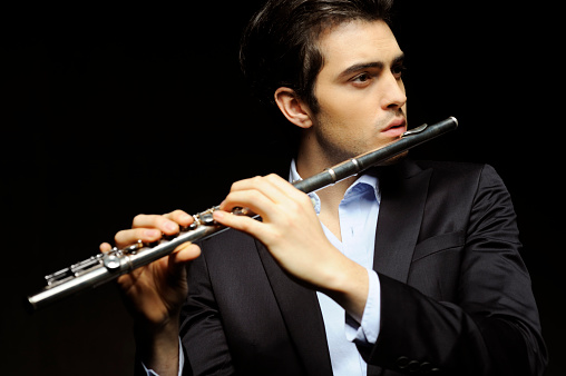 Young man playing flute.  Copy space. 