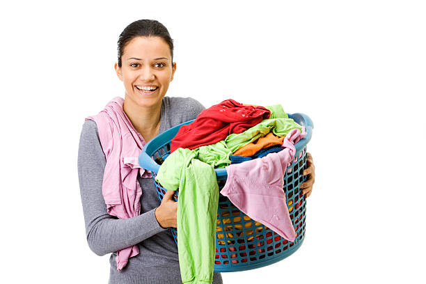 Beautiful young black woman folding laundry in the living room at home.