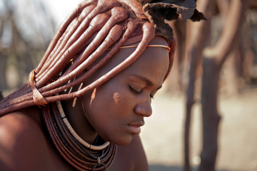 Cheerful Himba woman smiling, dressed in traditional style at her village in Namibia, Africa.