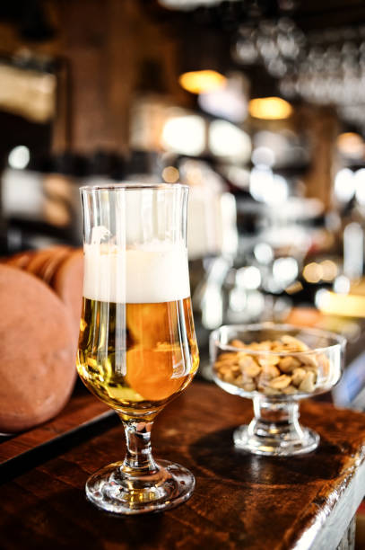 bicchiere di birra sul bancone - beer nuts foto e immagini stock