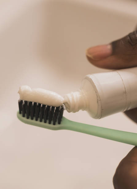 istock African american male hand holding toothbrush with toothpaste applied on it in bathroom. Close up of man hand ready for brushing teeth. Guy hand holding toothbrush with white tooth paste. 1551483437