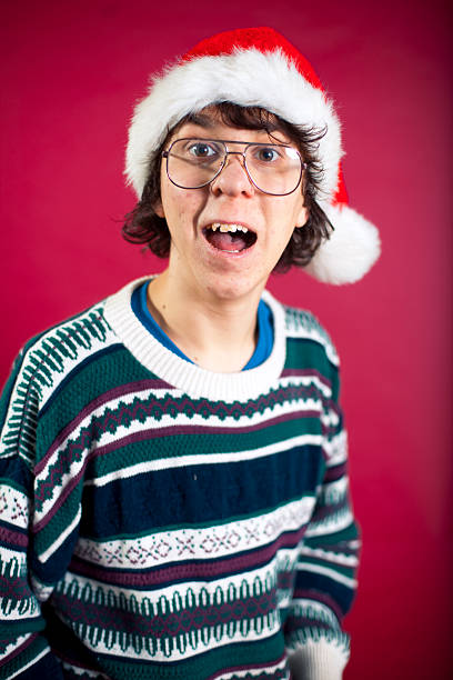 Ugly Christmas Sweater Nerd Nerdy Christmas teen wearing ugly sweater and santa hat. christmas nerd sweater cardigan stock pictures, royalty-free photos & images