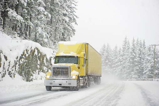 Semi truck driving in severe road conditions during a blizzard