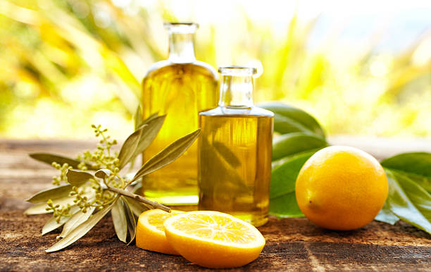 Massage oil bottles with lemons and olive branch Massage oil bottles with lemons and green leaves at spa outdoors. Front view, Horizontal shot. massage oil photos stock pictures, royalty-free photos & images