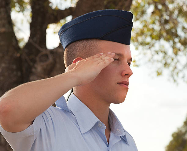 Bless you Airman's evening salute. Pic taken during the 5:00 playing of the United States national anthem. The United States Air Force uniform is being worn. Serious face of a young man in his 20's. air force salute stock pictures, royalty-free photos & images