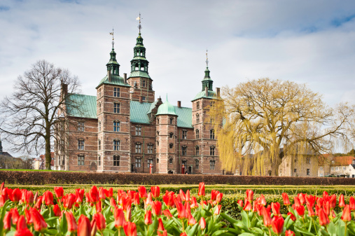 The renaissance spires of Rosenborg Castle overlooking the tranquil green oasis of Kongens Have, The King's Garden, with vibrant red tulips blooming in the spring sunshine. ProPhoto RGB profile for maximum color fidelity and gamut.
