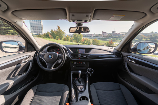 Vilnius, Lithuania - September 20, 2020: Interior of BMW X1 2012 Year compact sport utility vehicle. Beautiful Sunny Cityscape Background.