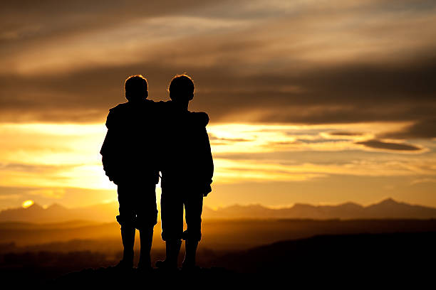 duas crianças assistir o pôr-do-sol sobre o horizonte - standing family golf loving - fotografias e filmes do acervo