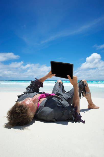 castaway homme d'affaires utilise une tablette sur la plage - reading beach e reader men photos et images de collection