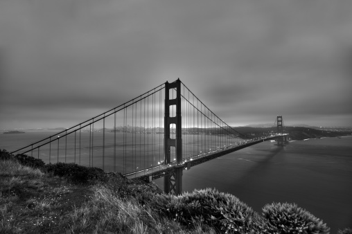 An aerial grayscale shot of the famous Golden Gate Bridge in San Francisco  covered by fog in summer