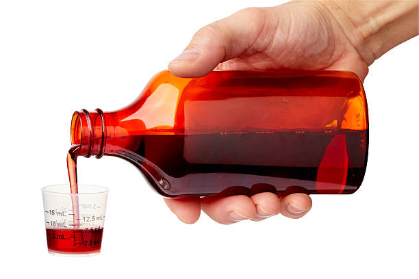 Cough Medicine Hand pouring cough medicine into graduated cup. Larger files come with clipping path. Professionally shot, color corrected, exported 16 bit color and retouched for maximum image quality. child liquid medicine stock pictures, royalty-free photos & images