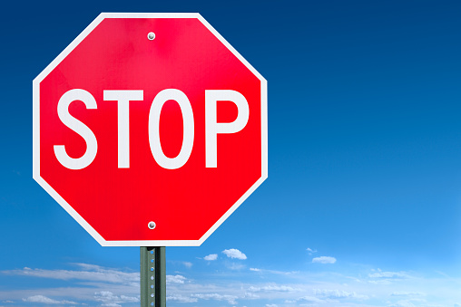 A stop road sign post over a clear blue sky with some clouds at the horizon - a clipping path is included to separate sign from bkg.Canon 5D MarkII. This was photographed in the USA. Image cleaned up and composed over sky using Photoshop.