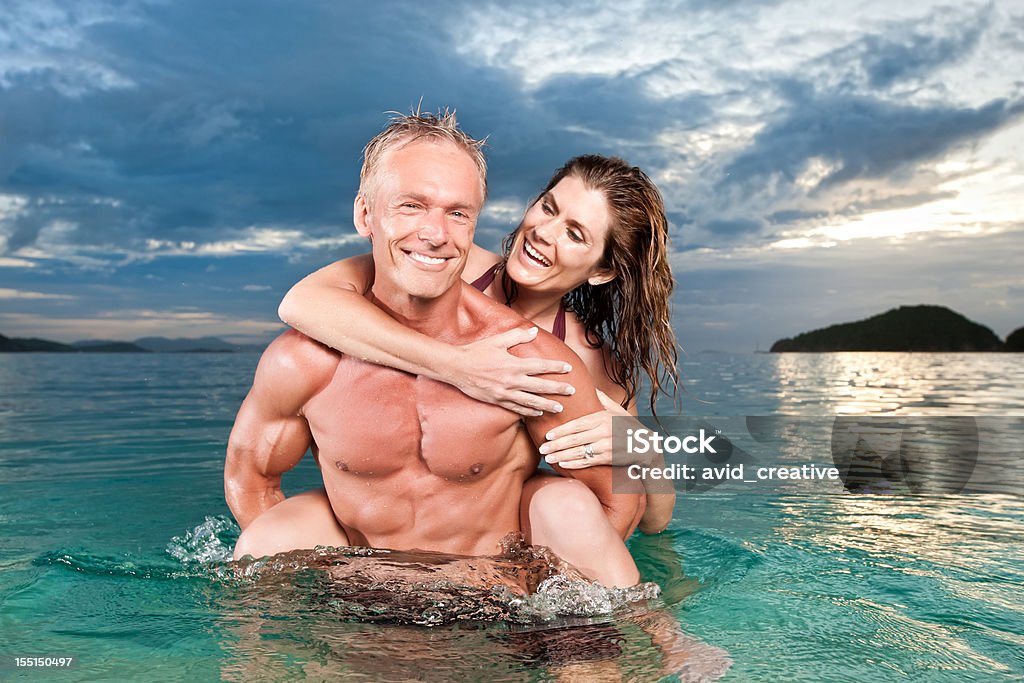 Couple ludique dans l'océan au coucher du soleil - Photo de Musclé libre de droits