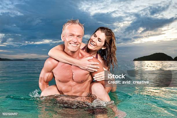 Photo libre de droit de Couple Ludique Dans Locéan Au Coucher Du Soleil banque d'images et plus d'images libres de droit de Musclé - Musclé, Plage, Tous types de couple