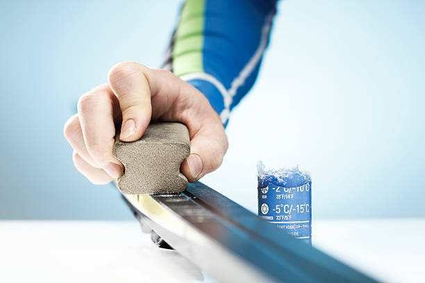 A man rubbing wax on his cross country skis stock photo