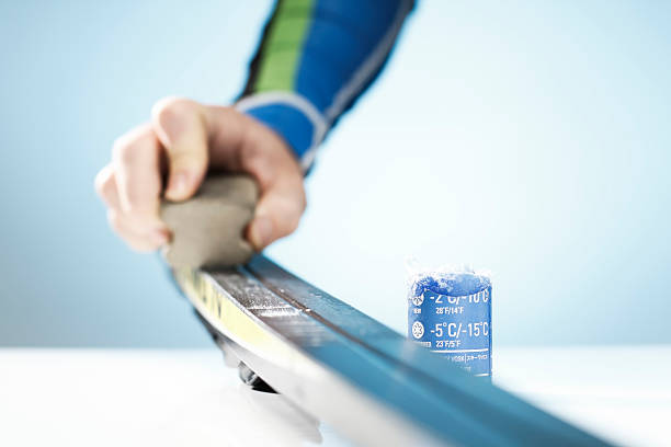 Man waxing his cross-country skis on a table stock photo