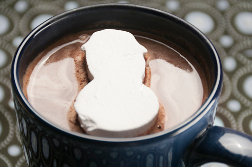 Close-up of a marshmallow snowman in a mug of hot chocolate.