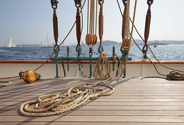 Classic Sailing yacht deck and view Rope coiled on the teak decking on a classic sailing yacht, with rigging, and view to other yachts in the background. Depth of field with focal point on foreground. Please see my other deck photos...  boat deck stock pictures, royalty-free photos & images
