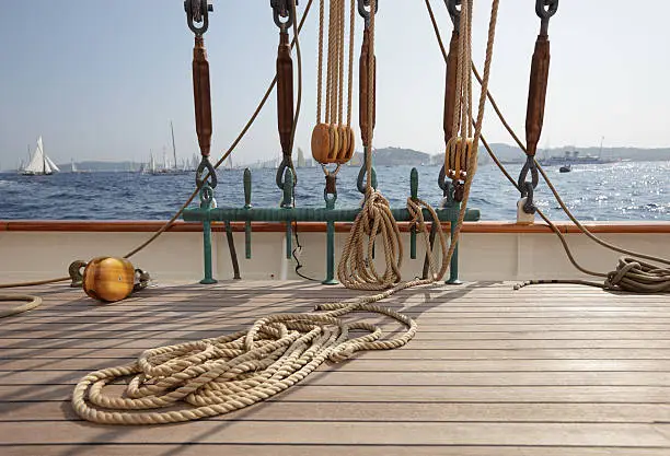 Rope coiled on the teak decking on a classic sailing yacht, with rigging, and view to other yachts in the background. Depth of field with focal point on foreground. Please see my other deck photos... 
