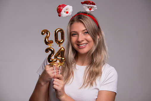 Portrait of young woman holding 2024 numbers for new year. New Year 2024. isolated on gray background
