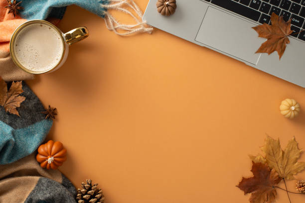 istock Autumn-themed freelance setup featuring a laptop, coffee cup, cozy scarf, and rustic decor of pumpkin candles, maple leaves and pinecones on brown background, ideal for text or advert placement 1551510688