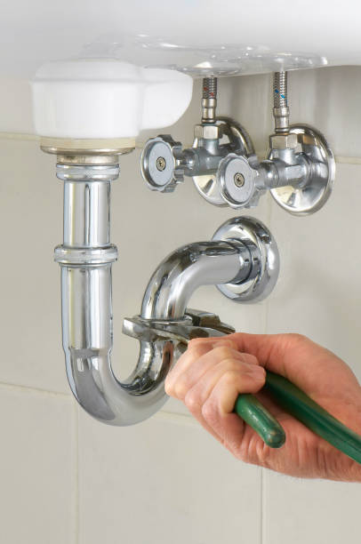 Hand of a plumber fixing a sink with green tool stock photo