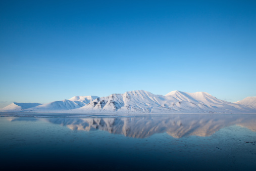 Spitzbergen mountain reflection in  Isfjord, winter landscape, bright weather image with plenty of copy space.