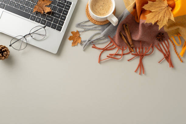 istock Autumn-themed workspace. Laptop, spectacles, warm plaid, coffee mug, yellow maple leaves, pine cone, cinnamon sticks, anise arranged from top view on soft grey backdrop with space for text or advert 1551512455