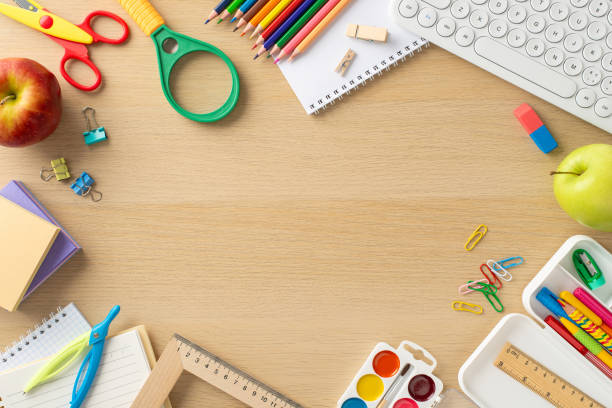 istock Embrace the flexibility of online studying from home with this top-view photo featuring a keyboard, notepads, snacks, paints and academic supplies on wooden background. Empty space for text or ads. 1551513521