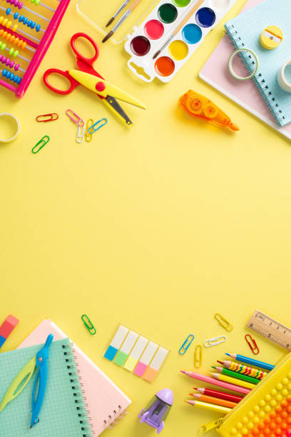 istock Discover the joy of education for small kids through this top view vertical image: a captivating arrangement of vibrant school supplies on a sunny yellow surface, with space for text or promotions 1551516701
