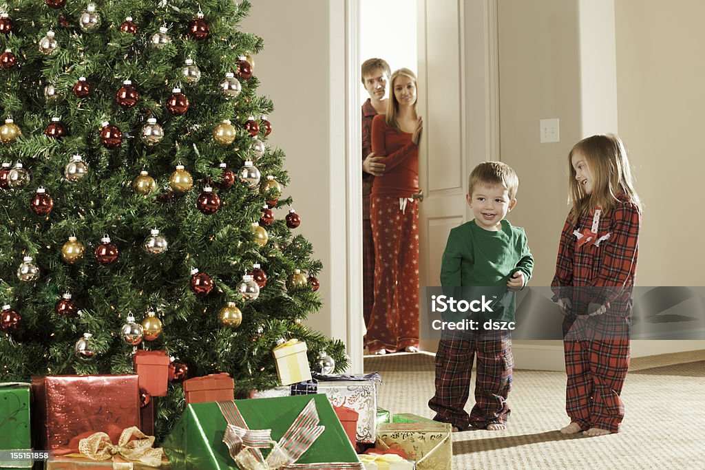 Christmas morning excited children while parents watch excited children on Christmas morning while parents watch 2-3 Years Stock Photo