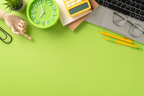 istock Explore the possibilities of remote learning with this top-down snapshot displaying a laptop, clock and various stationery on light green background. Utilize the copy-space for text or advertisements 1551519371