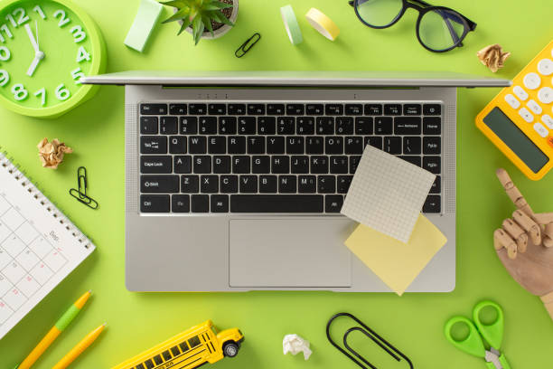 istock Engage in remote learning with this top-view shot, showcasing a laptop, calendar, clock, glasses and stationery like calculator, notes stickers, pens, paper clips on isolated light green background 1551519889