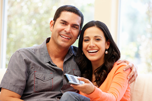 Hispanic couple watching television smiling