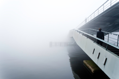 man walking on a bridge in the fog