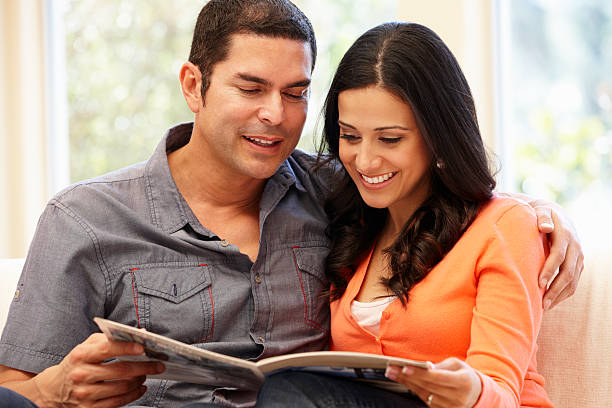 Hispanic couple at home reading magazine smiling