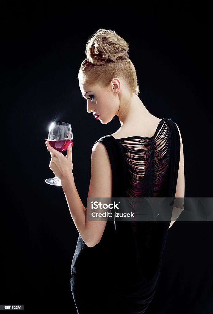 Beautiful woman with wineglass Glamour portrait of beautiful young woman wearing evening gown and holding glass of red wine. Black background. Women Stock Photo