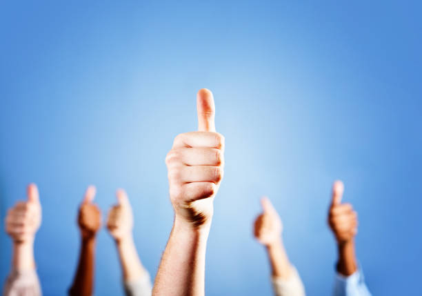 istock Many hands give approving thumbs-up sign against blue 155152579