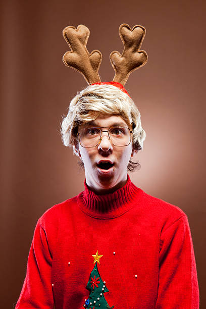 Surprised Reindeer Christmas Boy Surprised goofy reindeer boy looks at camera with a surprised facial expression. vintage nerd with reindeer sweater stock pictures, royalty-free photos & images