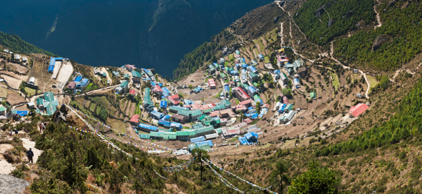 Panoramic high angle view over the tea houses and lodges, hotels and trails, prayer flags and temples of Namche Bazaar, Sherpa village, trading post and iconic gateway to Everest high in the Himalaya mountains of the Sagaramatha National Park, Nepal. ProPhoto RGB profile for maximum color fidelity and gamut.