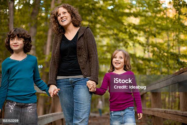 Sonriendo Madre E Hijas Caminando En Puente De Madera Al Aire Libre Foto de stock y más banco de imágenes de 30-34 años