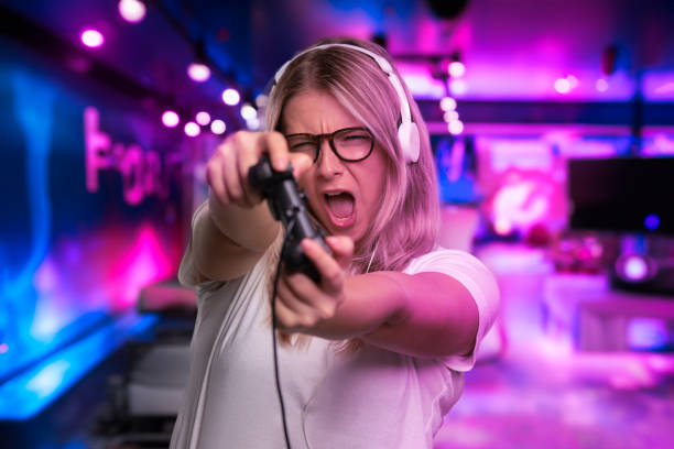 Young girl gamer in headphones with joystick playing computer game
